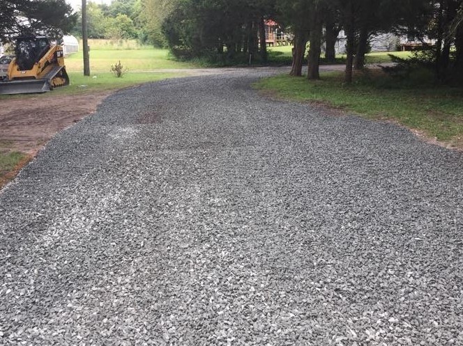 Stone driveway recently installed with skid steer in the background